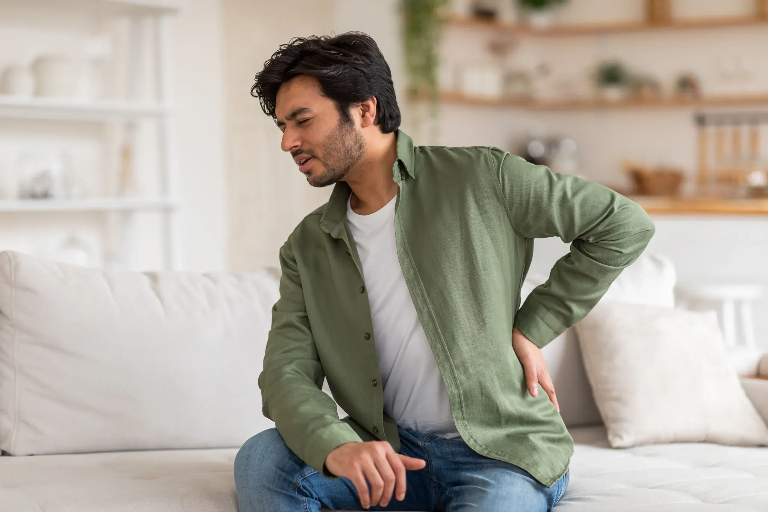 Patient holding lower back demonstrating herniated disc symptoms