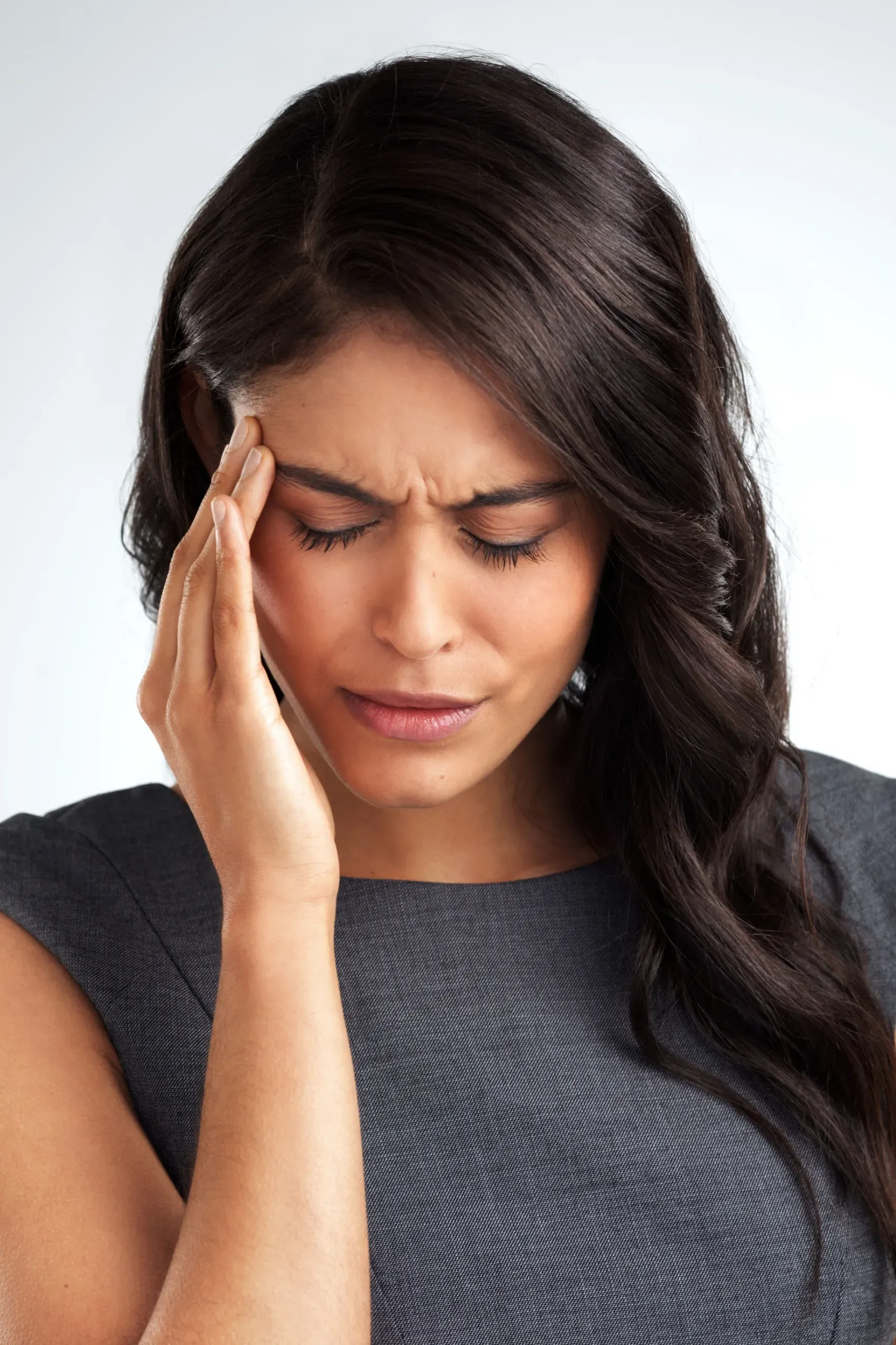 Woman rubbing her temples at a kitchen table representing brain fog symptoms at Resurgent Health Fargo
