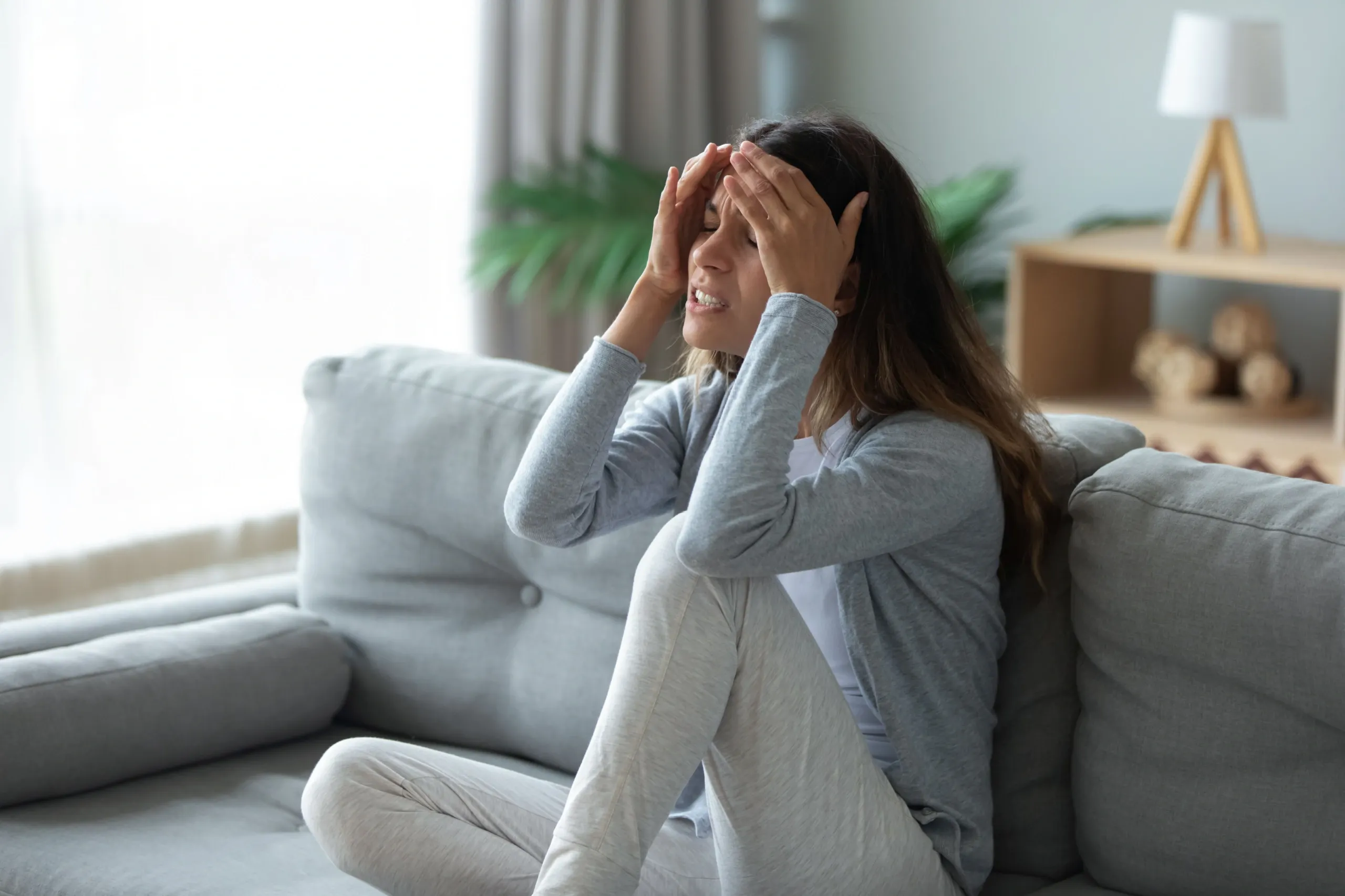 Woman experiencing chronic migraine symptoms holding her head