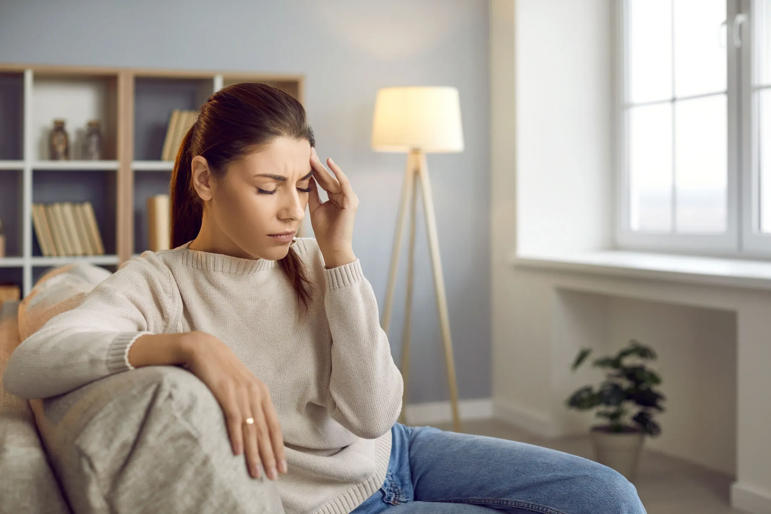 Woman holding her temples experiencing a headache near Spine-Ability Apollo Beach