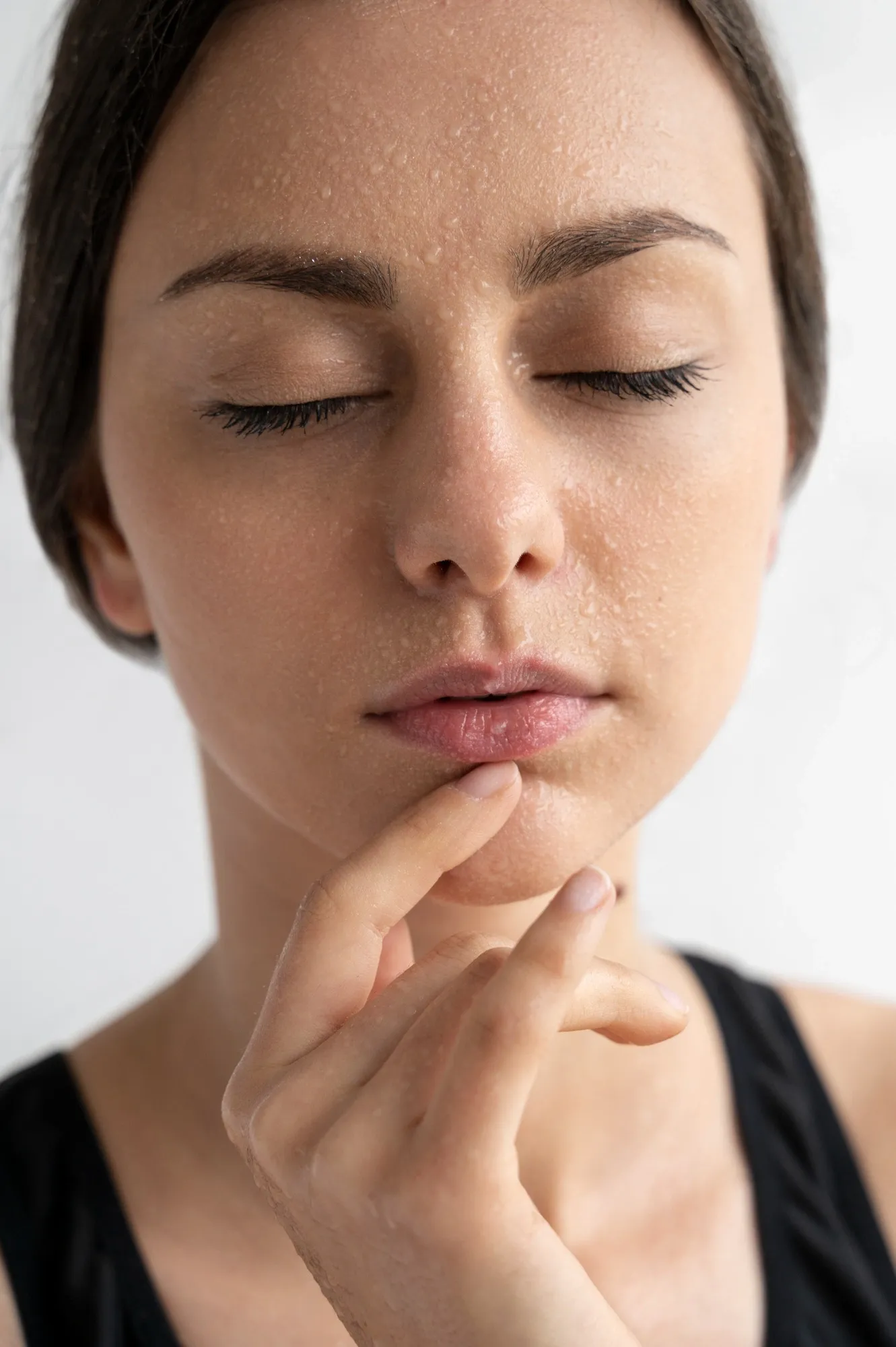 Woman examining her skin in a mirror, noticing oily patches and visible pores