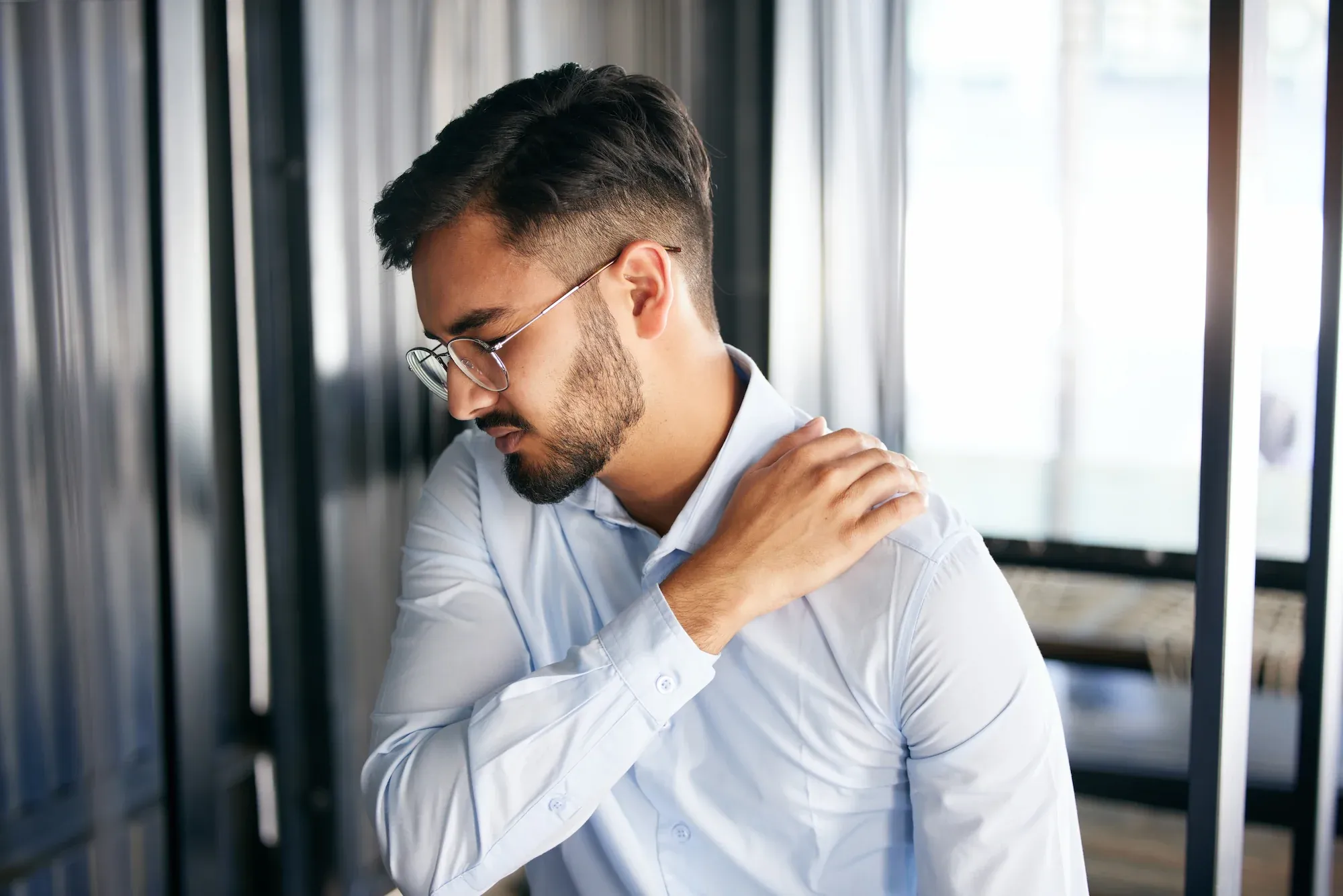Adult holding a stiff, painful shoulder at Reliance Primary & Urgent Care Jacksonville