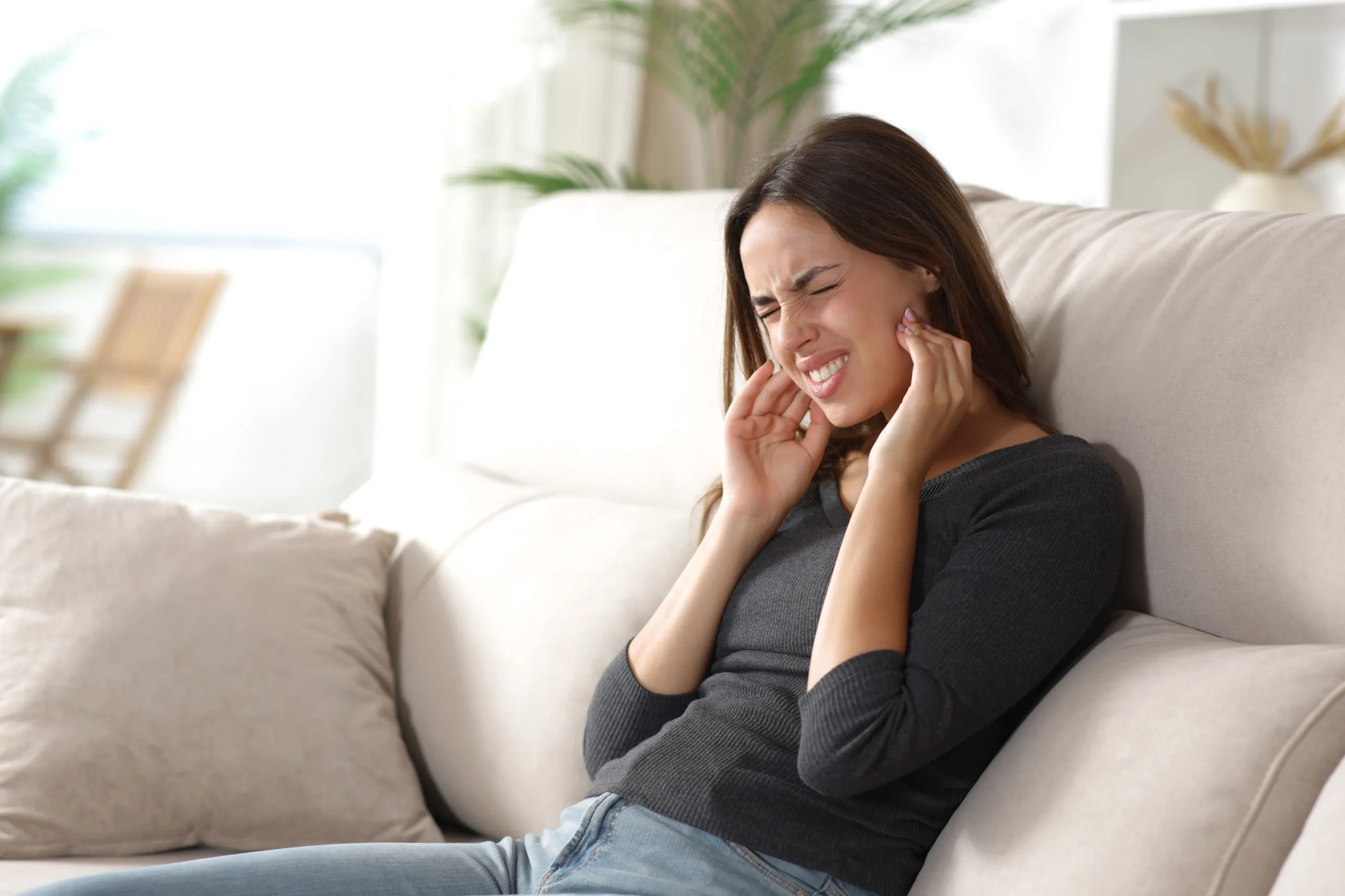 Patient holding jaw with mild discomfort during a TMJ consultation at Cook Family Dentistry in Santa Rosa Beach, FL