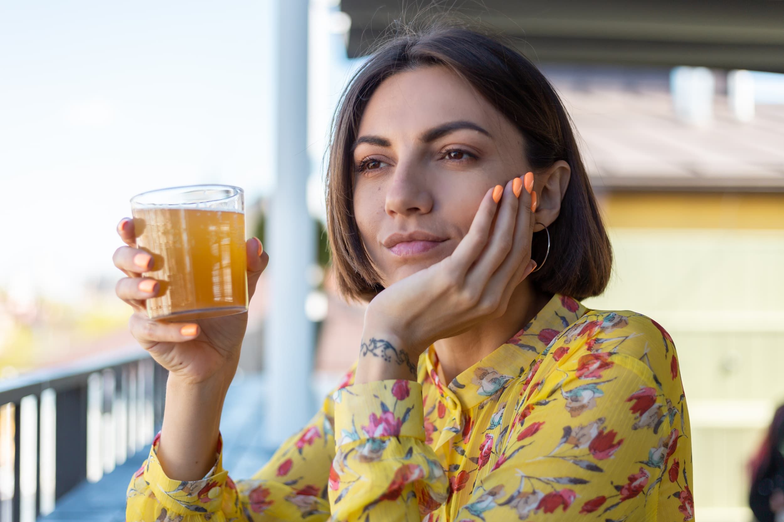 Woman holding a cold drink and touching her jaw due to tooth sensitivity