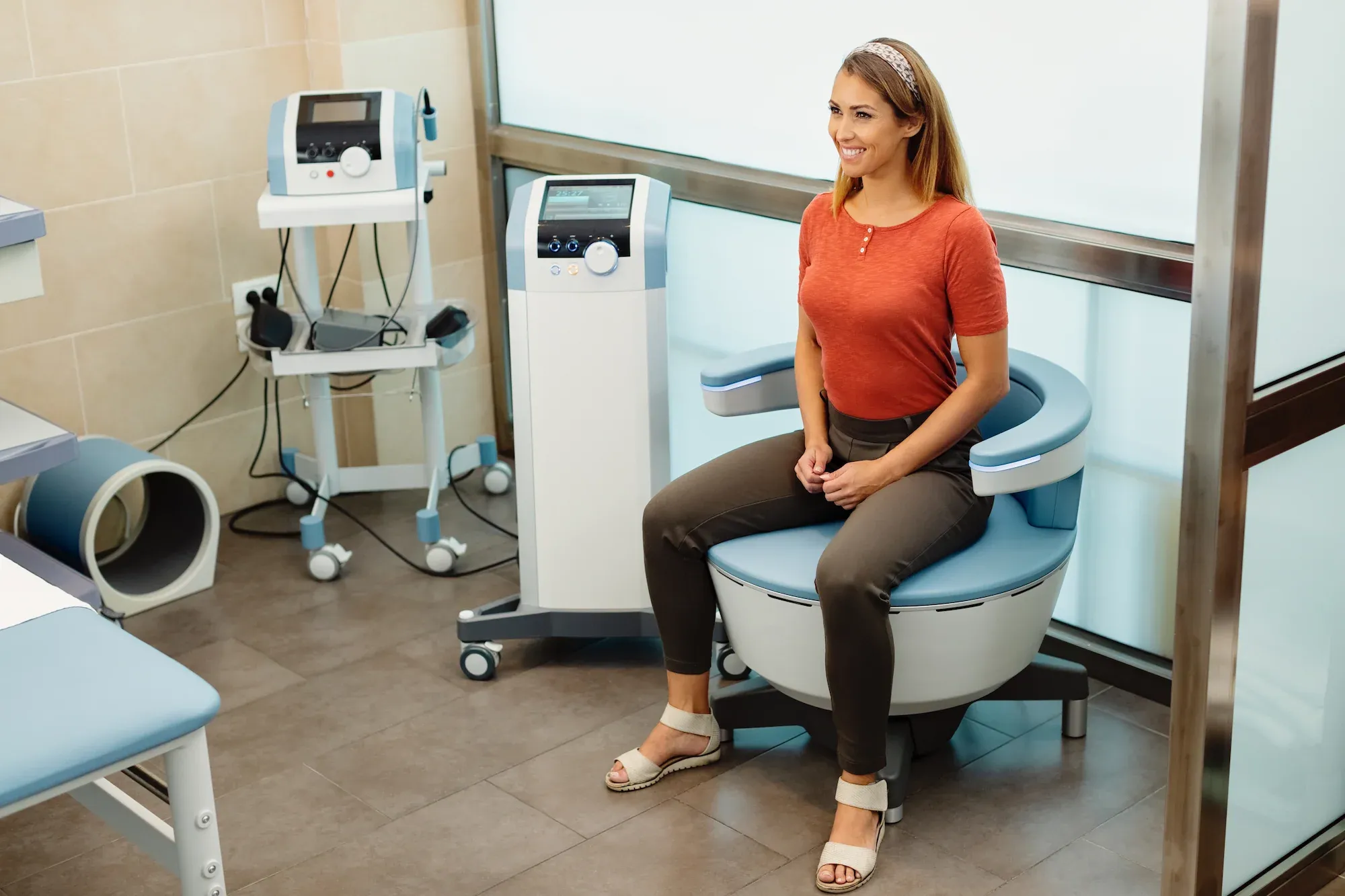 Patient seated on Emsella chair for pelvic floor therapy at Precision Chiropractic in Rockford MI
